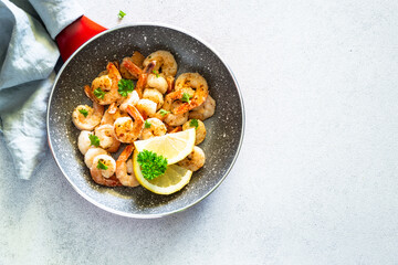 Frying shrimps with lemon in the frying pan. Top view image on white background.