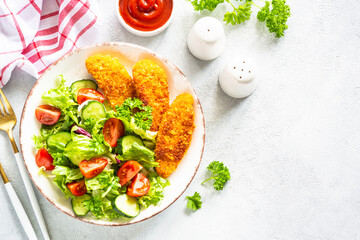Chicken nuggets with fresh salad and ketchup sauce at white table. Top view image with copy space,