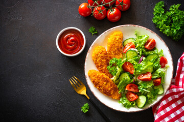 Chicken nuggets with fresh salad at black background. Top view image with copy space.