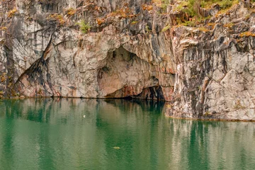 Malerische Vegetation an einer steilen Felswand und ein See am Fuße der Klippe © Yury Kisialiou