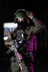 Army soldier in Combat Uniforms with an assault rifle and combat helmet night mission dark...