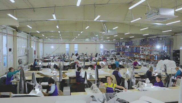 Large sewing production timelapse. There are many seamstresses in the workshop. Garment factory interior. Women in the sewing industry