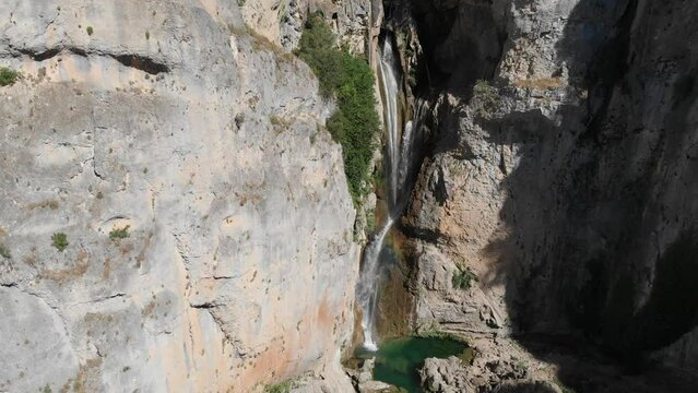 Tilt down shot of Salto de los &Oacute;rganos waterfall, as clean water cut through the rocks forming a pond at the bottom of the cliffs.
