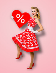 Woman holding red paper heart shape with % sign. Full length body portrait of happy pin up girl....