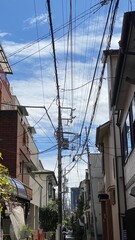 The narrow street of Tokyo, Nezu district year 2022 on a sunny day with clouds, street wires and varieties of retro houses