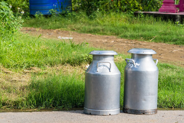 Aluminum bidons for milk stand against the background of a fence in the courtyard