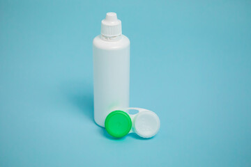 Packages with contact lenses, case and drops on blue background