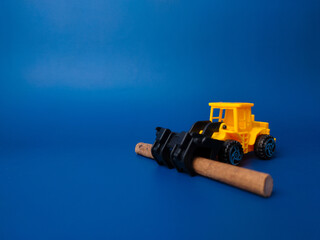 Fototapeta premium Excavator with wooden stick on blue background with copy space. Conceptual image of illegal logging.