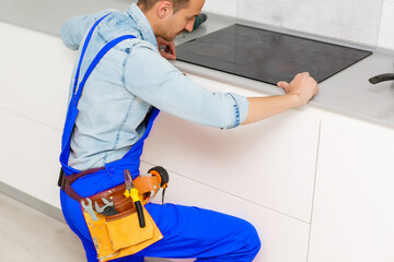 a worker repairs an electric stove, Induction Stove.