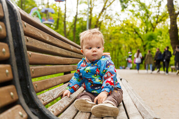 portrait of a little boy in the park on a bench catching soap bubbles