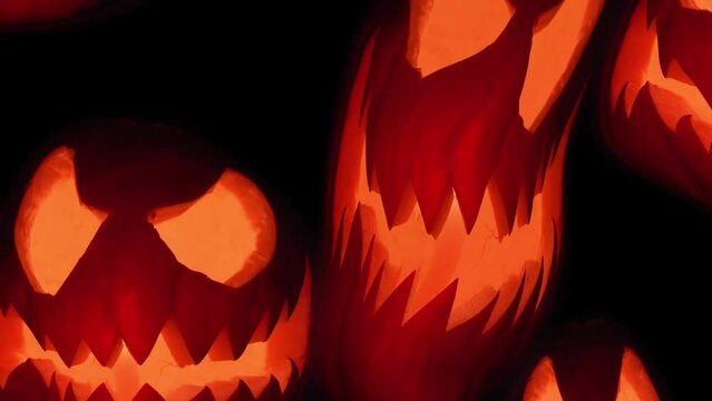 Halloween pumpkin spooky faces with candle light flying up on black background. Orange scary Jack O Lantern 4K.