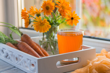 Carrot juice in a glass and fresh carrots on the table.
