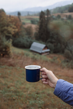 girl holding a cup of coffee against the backdrop of a mountain landscape