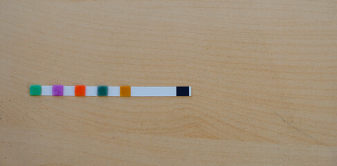The wet test strip for the pool is on a wooden surface. Pool chemistry concept. Copy space. 