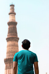 Delhi, India-may 12, 2021: A Young man looking up at qutub minar in delhi