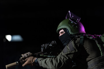 Army soldier in Combat Uniforms with an assault rifle and combat helmet night mission dark...