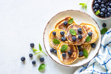 Pancakes with fresh blueberries and honey at white table. Healthy breakfast or dessert. Top view with copy space.