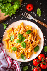 Pasta with tomato sauce, basil and parmesan with ingredients for cooking on dark table. Flat lay, vertical.