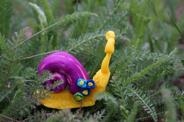 Snail figurine decorated with a flower on a background of green grass. Springtime.