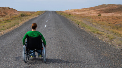 Woman in a wheelchair on a highway in the steppes. 