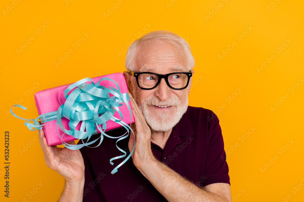 Sticker Photo of handsome senior man shake present wonder guess look empty space isolated over yellow color background