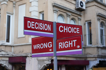 Four street signs,  sign post,  sign the post with four signs in front of shops on the street, Iron, metal intersection sign with four arrows. "Decision, Choice, Wrong, Right"