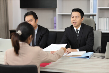 Human resources department managers sitting and interviewing female businesswoman applicant or candidate during job interview in modern office (Focus on female candidate). Business recruitment concept