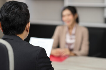 Rear view human resources department managers sitting and interviewing female businesswoman...