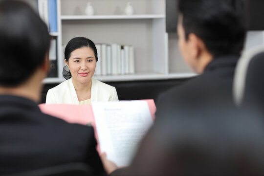 Human resources department managers sitting and interviewing female businesswoman applicant or candidate during job interview in modern office (Focus on female candidate). Business recruitment concept