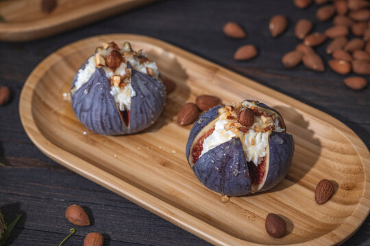 Fresh ripe raw figs with mascarpone cheese, almonds and honey or maple syrup in wooden tray.