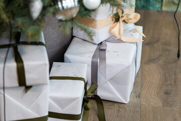 Beautiful Christmas gift boxes on floor near fir tree in room.