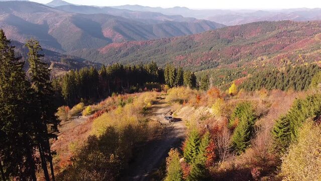 SUV rides off-road with a sharp turn in the mountains on a sunny autumn day — aerial footage