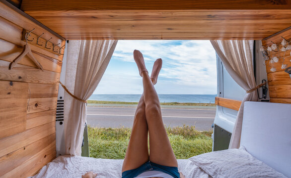 Detalle de piernas de mujer irreconocible, acostada en la camper, con vistas al mar. Fotograf&iacute;a horizontal con copy space.