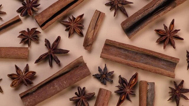 Rotating background with cinnamon sticks and anise stars on a beige background,cozy food spicy trendy background