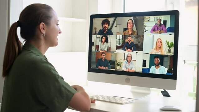 View above shoulder on a computer screen with a multiracial team. Female freelncer employee has remote meeting with diverse employees, virtual conference, webinar via video call on computer