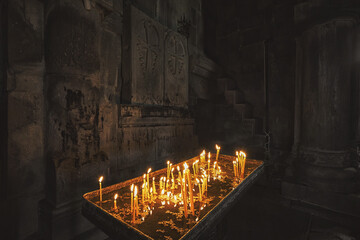 Burning candles in the dark prayer hall at armenian church