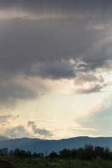 Thunderhead covers the Balkans. Downpour is approaching agricultural land. Villages, fields and forests of Bulgaria before the rain. The terrain in southern Europe. Panorama.