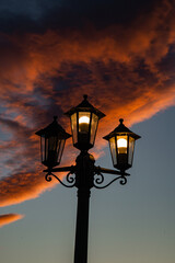 Fototapeta na wymiar old broken street lamp on a bright orange sunset background