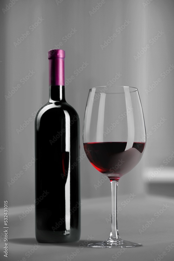 Poster Bottle of tasty red wine with a glass on desk