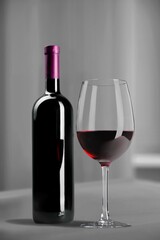 Bottle of tasty red wine with a glass on desk