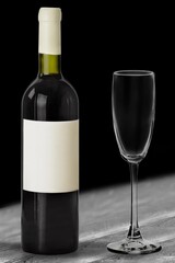 Bottle of tasty red wine with a glass on desk