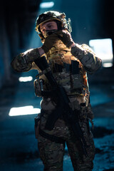 Army soldier in Combat Uniforms with an assault rifle and combat helmet night mission dark...