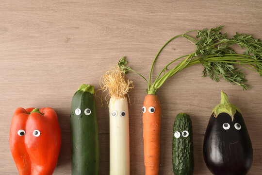 Background with funny vegetables with eyes on wooden table top