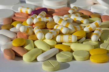 Pile of medical pills in white, yellow and other colors. Healthcare and medicine concept.