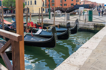 Fototapeta na wymiar Gondolas moored on the street of Venice, a row of Venetian houses and a cloudy sky in the morning in Venice, water transport, tourist travel in Italy, European landmarks