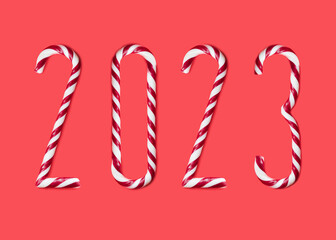 New year 2023 made from sweet caramel canes, candies on red background
