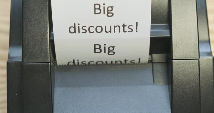 Receipt printer prints text: big discounts. Close-up, front view. The concept of promotions, sales in stores.