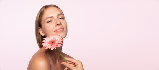 Beautiful young girl with glossy blond hair holding flower isolated over white background. Shapes and lines, cosmetics, natural beauty