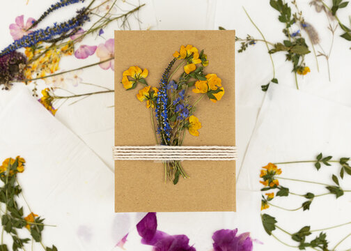 A Gift Box Made Of Craft Paper Is Decorated With Dried Pressed Flowers And Tied With A Rope. DIY Gift Idea.