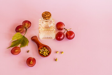 organic grape seed oil in a glass bottle of light embossed glass with cork. pink background. the concept of natural care, moisturizing, massage.